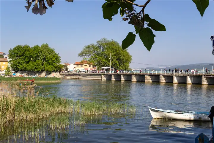 Gölyazı'yı karaya bağlayan tarihi köprü ve kıyıdaki sazlıklar. Mayıs ayının tatlı kalabalığında köyü keşfetmeye köprüden geçerek başlıyoruz.