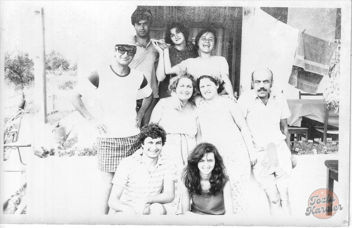 1980'lerin başında Avşa Adası'nda bir yazlık evin bahçesinde bir araya gelmiş, gülümseyen gençlerin ve yetişkinlerin nostaljik aile pozu.