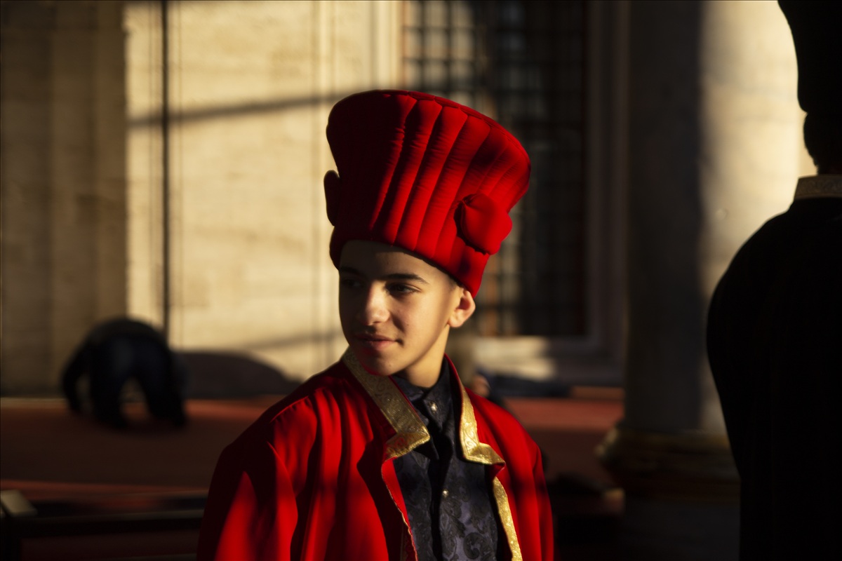 Üsküdar Mihrimah Sultan Camii avlusunda kadife kırmızı Osmanlı kavuğu ve işlemeli kaftan giyen çocuk.